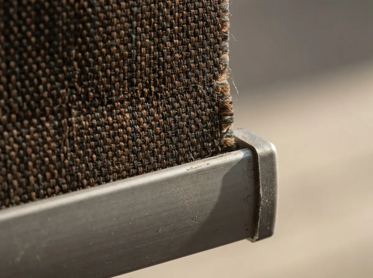 Extreme close-up of blockout roller blind fabric edge and aluminium bottom rail hardware, tobacco and charcoal tones